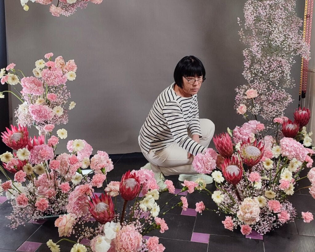 Флорист стоит на коленях перед букетом цветов